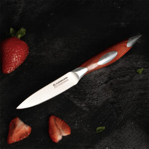 Steel paring knife with wooden handle, on a dark background with sliced strawberries