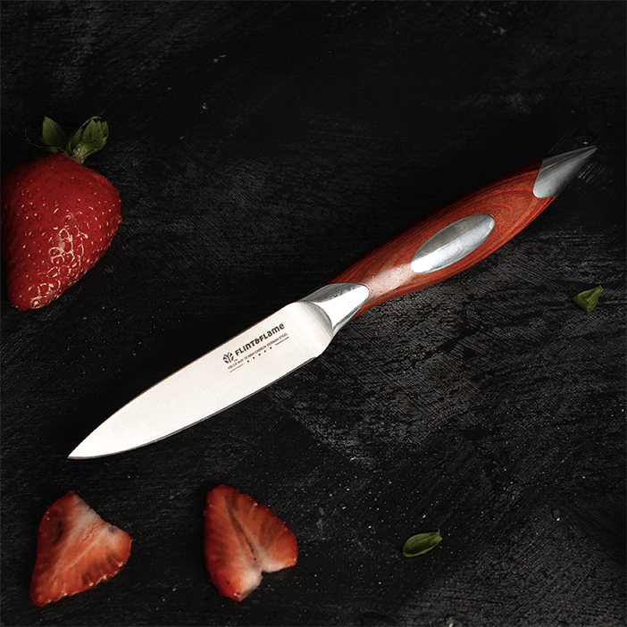 Steel paring knife with wooden handle, on a dark background with sliced strawberries