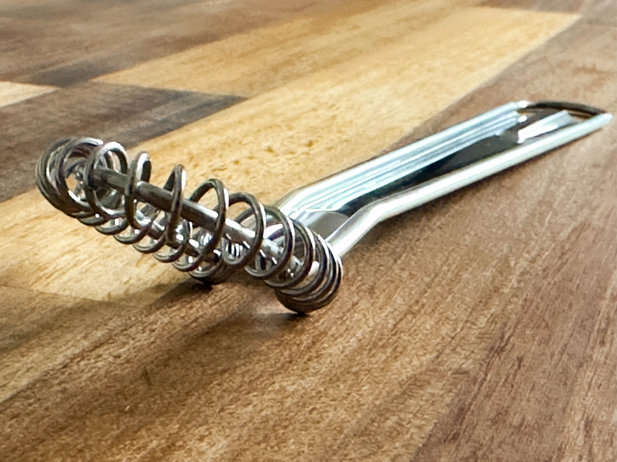 Metalic whisk with flat head for sauce making on wooden background